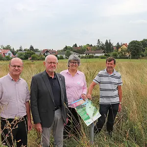 Drei Männer und eine Frau stehen in der Wiese.