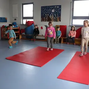 Drei Kinder laufen über eine dicke, eine dünne Matte sowie über den festen Hallenboden.