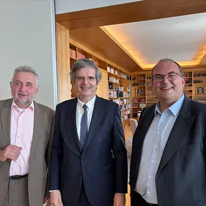 Drei Männer lächeln in der Botschaft im die Kamera