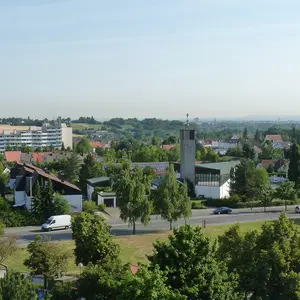 Blick vom Rathaus auf den Turm von St. Markus. Im Vordergrund grüne Bäume