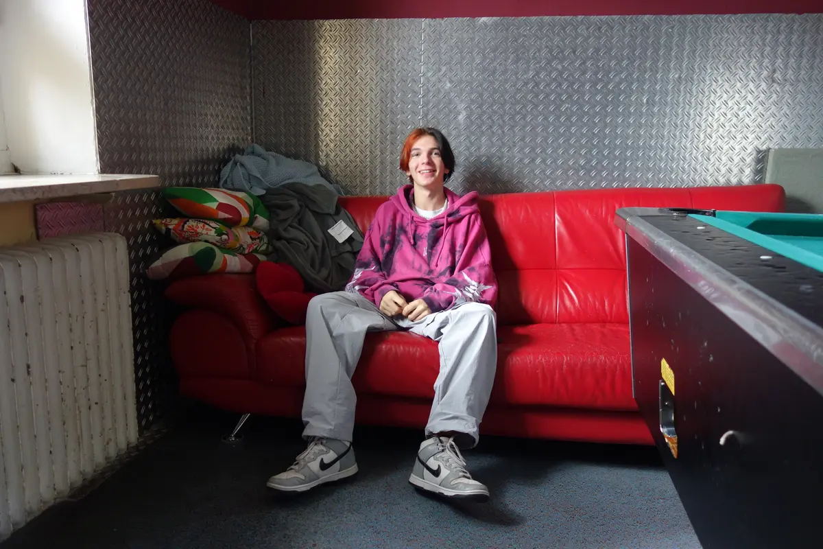 Chris Keller auf rotem Sofa neben Billardtisch im Jugendhaus 