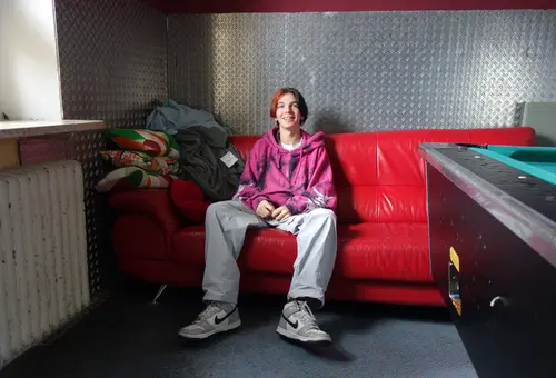 Chris Keller auf rotem Sofa neben Billardtisch im Jugendhaus 