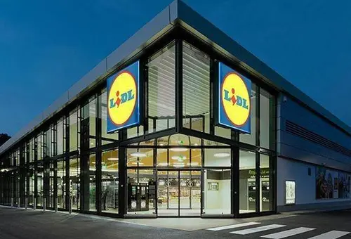 Beispielfoto des Eingangsbereiches einer Lidl-Filiale der aktuellen Generation mit vielen Glasfenstern.