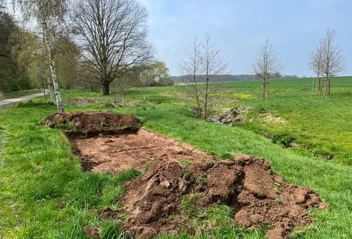 Eine Wiese, auf der ein breiter Streifen Boden freigelegt ist