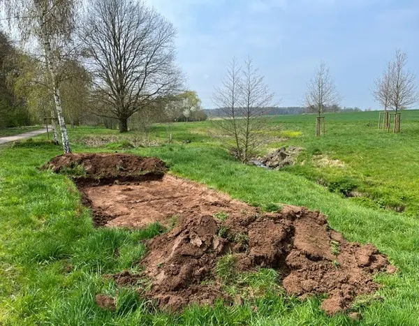 Eine Wiese, auf der ein breiter Streifen Boden freigelegt ist