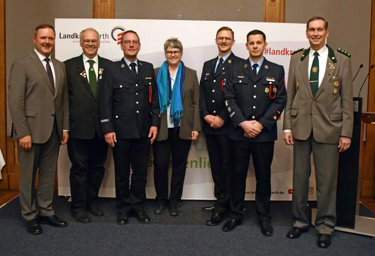 5 Herrren in Uniform. Ganz links Landrat im Anzug. Vierte von links Bürgermeisterin mit Anzug und Schal. 