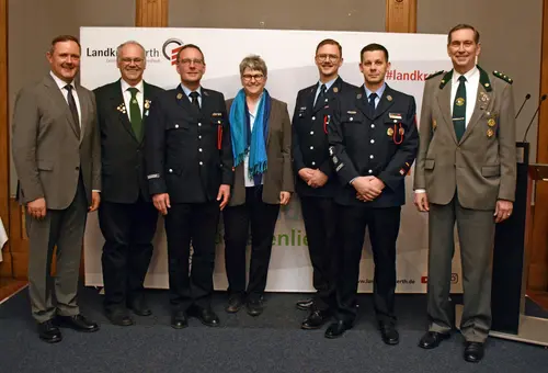5 Herrren in Uniform. Ganz links Landrat im Anzug. Vierte von links Bürgermeisterin mit Anzug und Schal. 