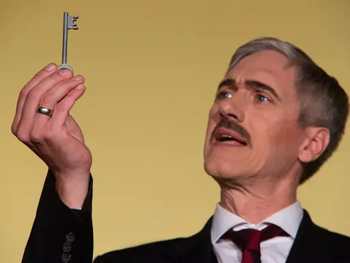 Ein Mann hält einen Schlüssel hoch und scheint etwas zu erklären.