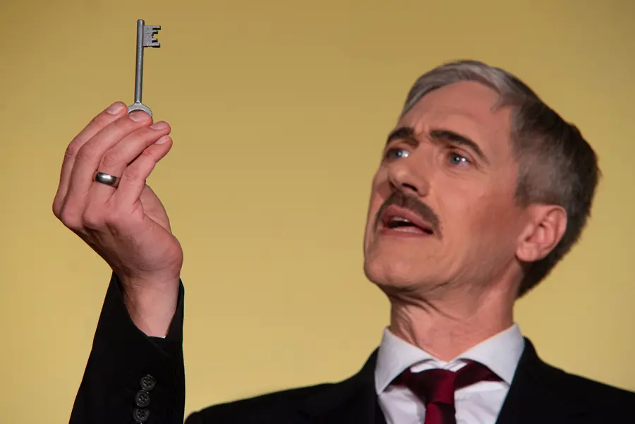 Ein Mann hält einen Schlüssel hoch und scheint etwas zu erklären.