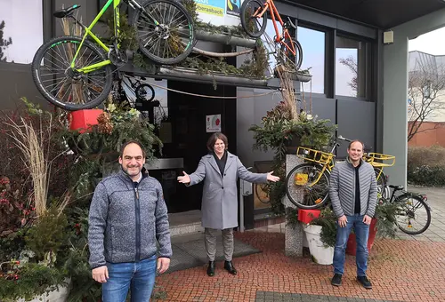 Erste Bürgermeisterin Birgit Huber steht mit den beiden Männern vor dem Rathaus und eutet einladend auf sie.Wolfstädter (links) und Daniel Morawietz.