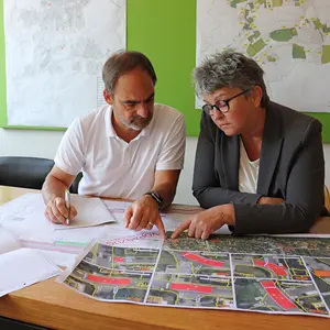 Mann und Frau bei der Durchsicht von Plänen an einem Schreibtisch