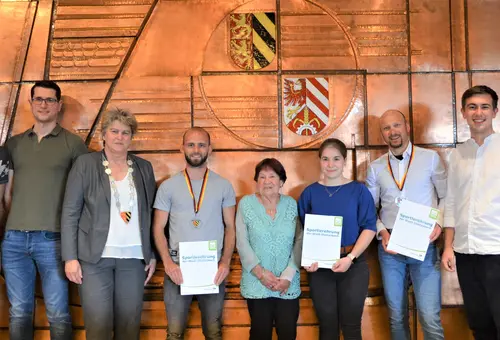 Acht Personen vor der Wand mit den Wappen der Stadt Oberasbach und des Landkreises Fürth