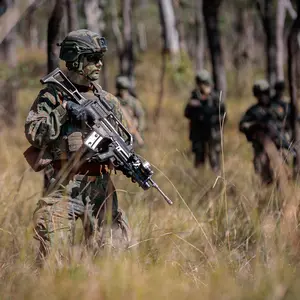 Soldat mit Gewehr im Wald, im Hintergrund weitere Soldaten