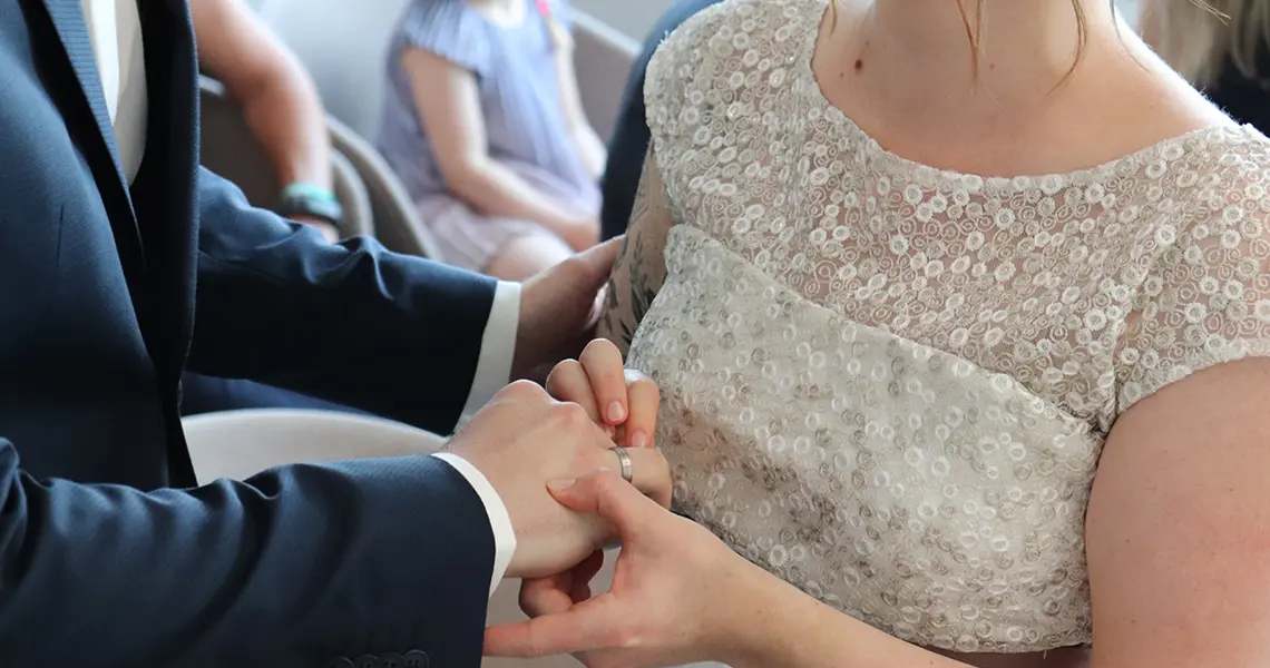 Die Braut steckt dem Bräutigam den Trauring an den Finger.