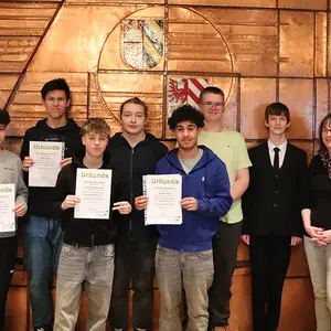 Sechs Schüler des Wahlausschusses halten ihre Urkunden in die Kamera,