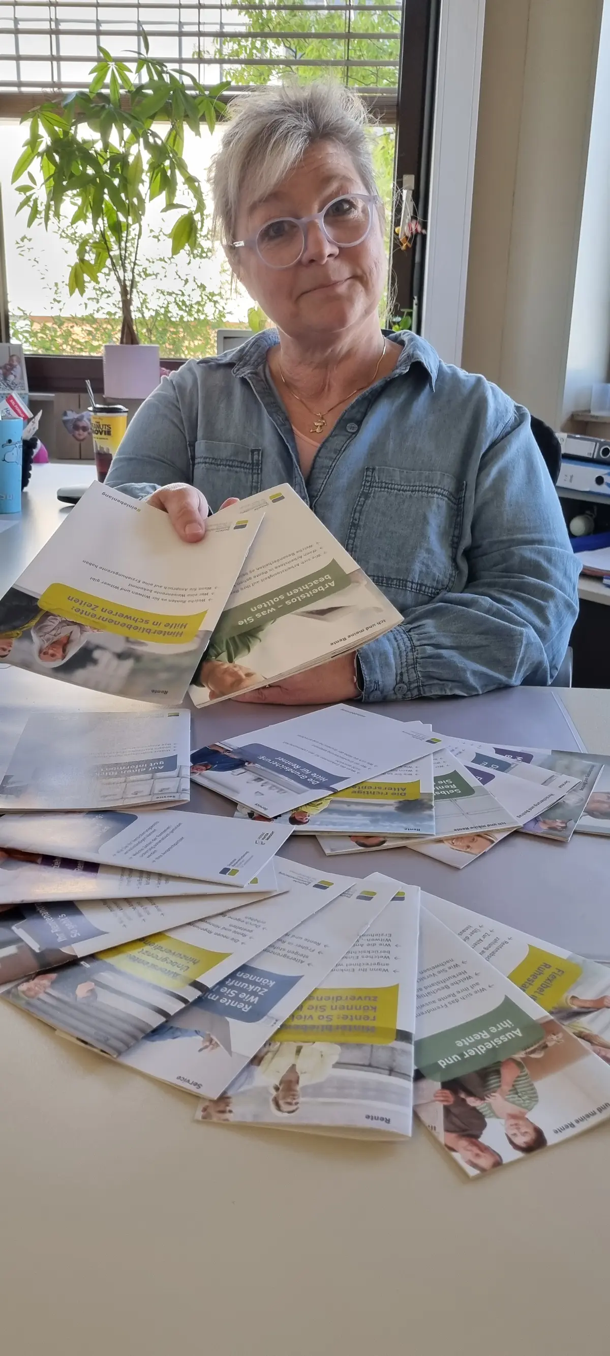 Mitarbeiterin reicht Broschüren über den Tisch 