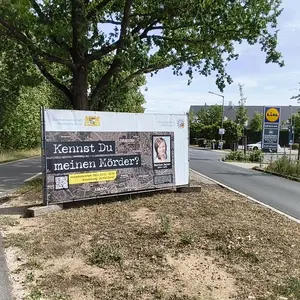 Seitenstreifen der Hainbergstraße mit dem Banner zum Cold Case. Darauf die Frage "Kennst du meinen Mörder?"