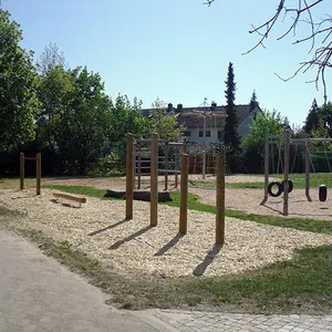 Im Vordergrund Turnstangen und Balancierbalken - im Hintergrund Reifenschaukeln und Vogelnestbaum