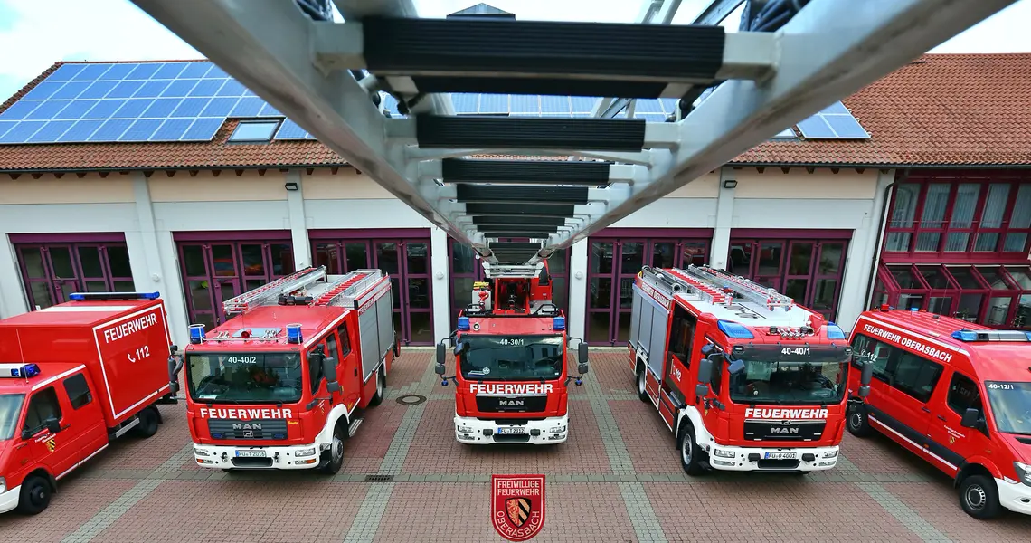 von der Spitze der Drehleiter blickt man auf die fünf Einsatzfahrzeuge der Feuerwehr