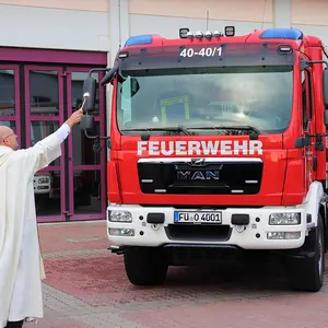 Der katholische Pfarrer Matthias Stepper segnet das neue Löschgruppenfahrzeug mit Weihwasser.