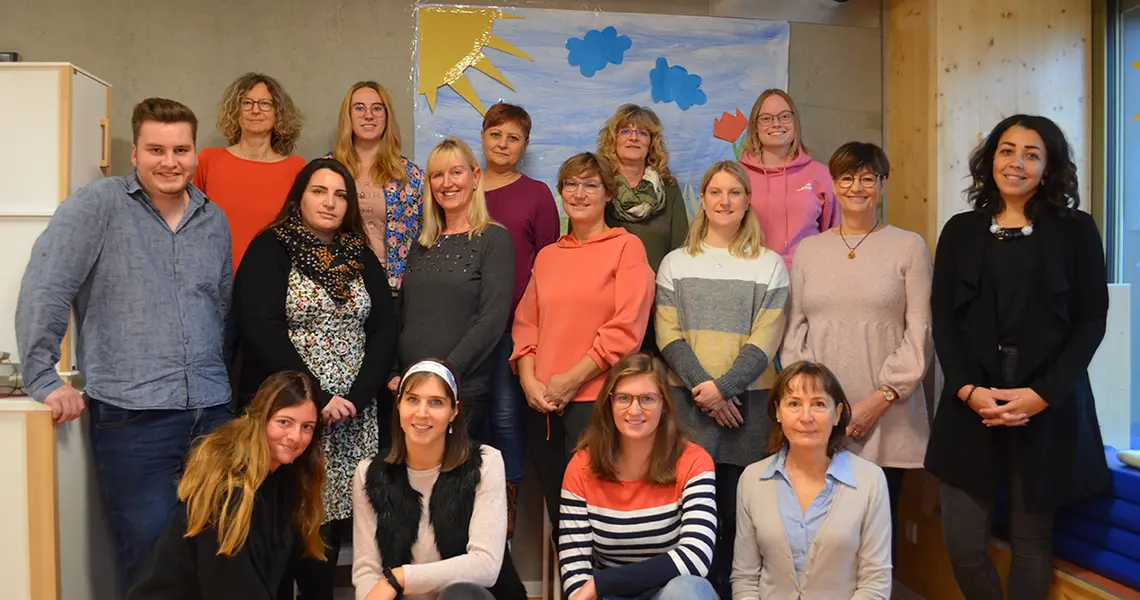 Die zahlreichen Erzieherinnen und Erzieher lächelnd beim Gruppenfoto