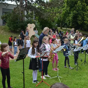 Eine Gruppe Kinder mit Blechblasinstrumenten auf einer Wiese.
