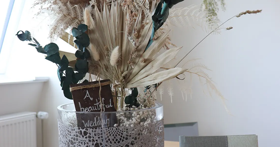 Ein Blumentopf mit künstlicher Deko auf dem Schreibtich, daneben das Familienbuch.