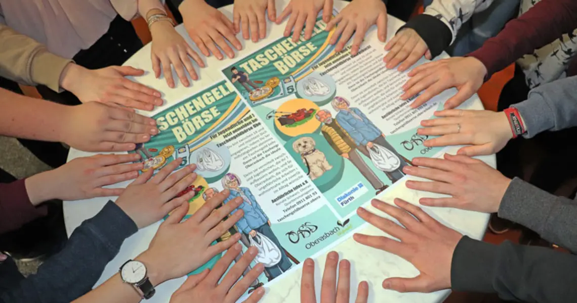 Helfende Hände im Kreis auf einer Tischplatte beim Handy-ABC