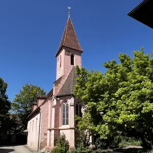 Kirche vor blauen Himmel und grünen Bäumen 