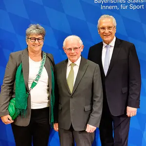 Zwei Männer und eine Frau im Anzug.