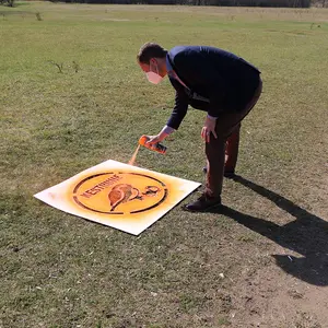 Landrat Matthias Dießl sprüht Logo auf eine Grasfläche am Hainberg