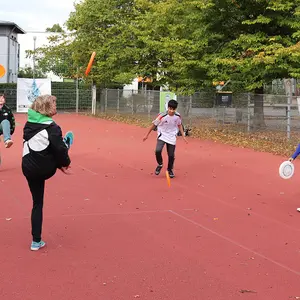 Coach und drei Kinder lassen den Frisbee durch die Luft fliegen