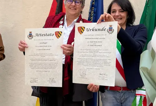 Zwei Frauen halten zwei Urkunden in die Kamera.