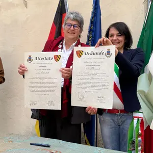 Zwei Frauen halten zwei Urkunden in die Kamera.