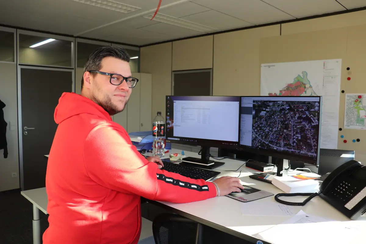 Marius Eberlein am Schreibtisch im Hintergrund ein Plan von Oberasbach 