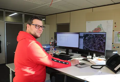 Marius Eberlein am Schreibtisch im Hintergrund ein Plan von Oberasbach 