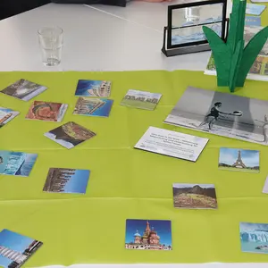 Auf einer grünen Tischdecke liegen Fotos von Hauptstädten und Naturszenen