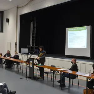 Birgit Huber am Rednerpult vor der Leinwand mit der Präsentation