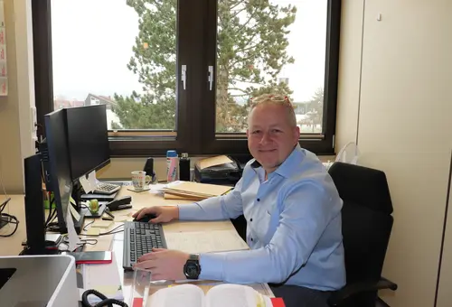 Heiko Bendel an seinem Schreibtisch, im Vordergrund ein Gesetzbuch. 