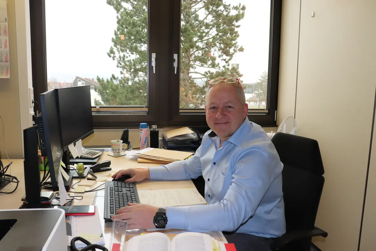 Heiko Bendel an seinem Schreibtisch, im Vordergrund ein Gesetzbuch. 