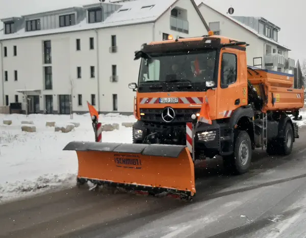 Oranger LKW des Bauhofes mit Schneeschild beim Winterdiensteinsatz im Ortskern von Oberasbach