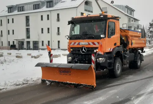Oranger LKW des Bauhofes mit Schneeschild beim Winterdiensteinsatz im Ortskern von Oberasbach
