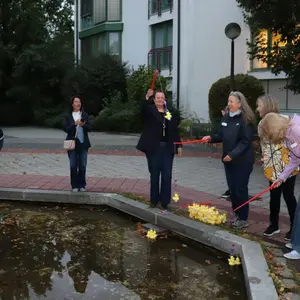 Frauen um einen Brunnen, in dem Gummienten schwimmen