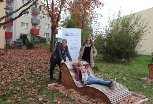 Zwei Frauen stehen um eine Wellenliege, eine dritte liegt entspannt darauf und verschränkt die Hände hinter dem Kopf. 