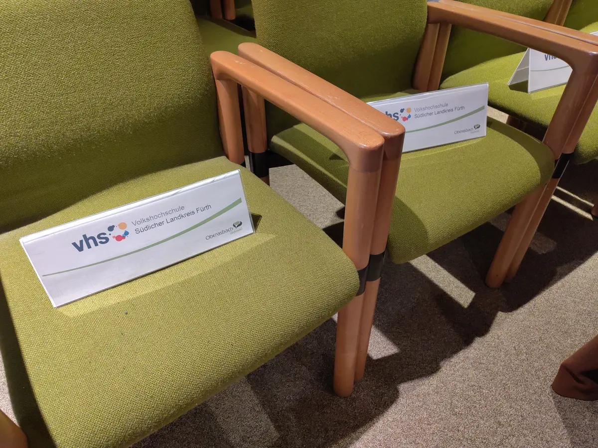 Zwei Besucherstühle im Sitzungssaal mit Reservierungsschildern der vhs 