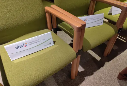 Zwei Besucherstühle im Sitzungssaal mit Reservierungsschildern der vhs 