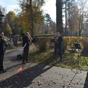 Die vier Mitglieder der Bläsergruppe des Posaunenchors Oberasbach, rechts neben ihnen die Versöhnungsglocke