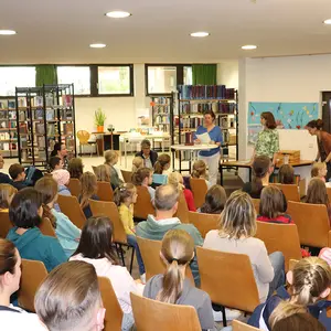 Blick von hinten auf die gefüllten Stuhlreihen in der Stadtbücherei.