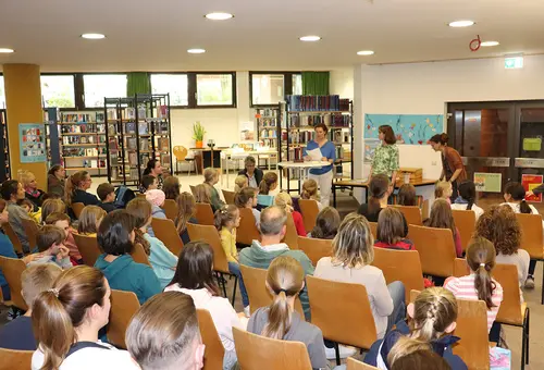 Blick von hinten auf die gefüllten Stuhlreihen in der Stadtbücherei.