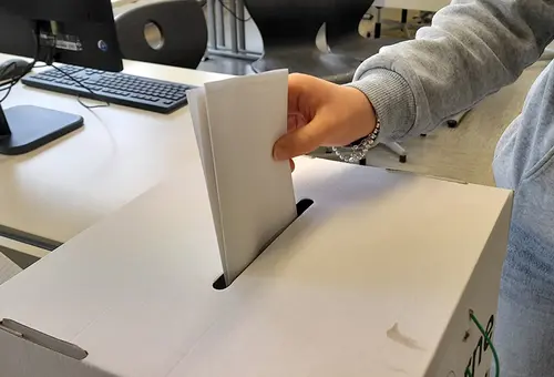 Eine Jugendliche wirft den Stimmzettel in die Wahlurne ein.